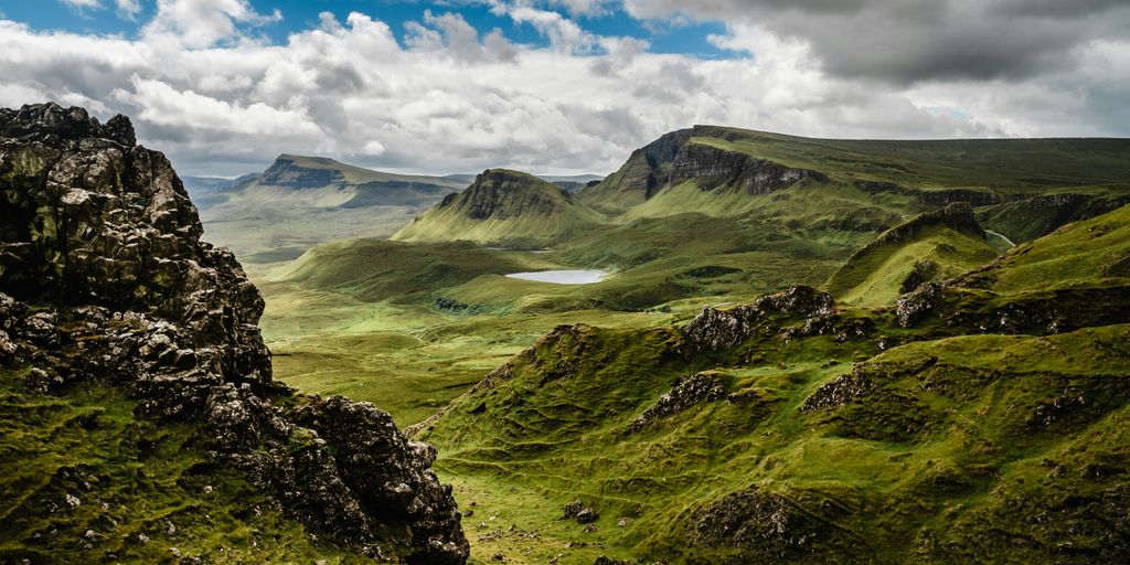 green grass on mountain under white cloudy sky